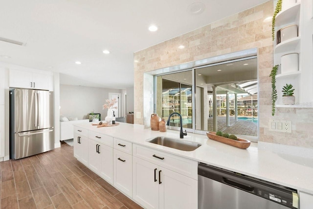 kitchen with stainless steel appliances, sink, wood-type flooring, and white cabinets