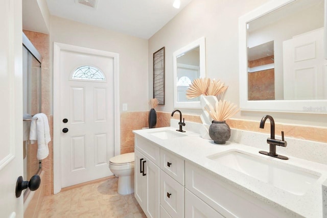 bathroom with walk in shower, vanity, toilet, and tile walls