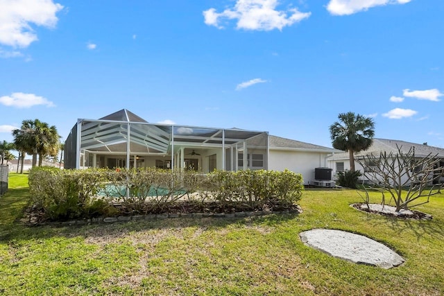 back of property with central AC, glass enclosure, and a lawn