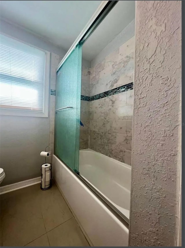 bathroom with tile patterned flooring, enclosed tub / shower combo, and toilet