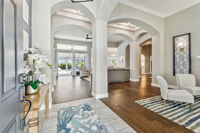 foyer entrance featuring ceiling fan, ornamental molding, light hardwood / wood-style floors, and a towering ceiling