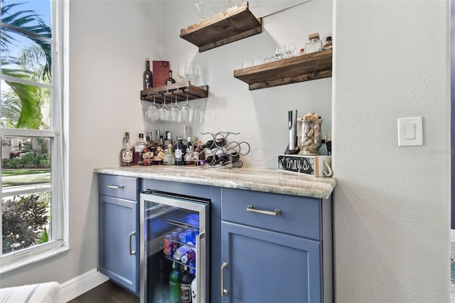 bar with blue cabinetry and beverage cooler