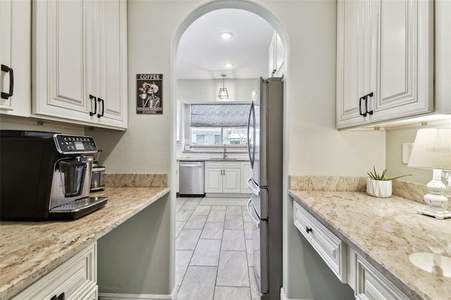 kitchen with light stone counters, sink, white cabinets, and appliances with stainless steel finishes