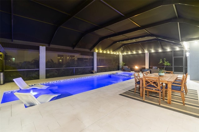 pool at night featuring a lanai and a patio area