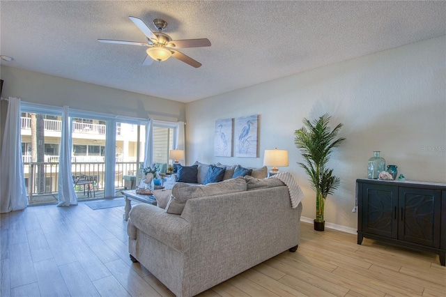 living room with ceiling fan, light hardwood / wood-style flooring, and a textured ceiling