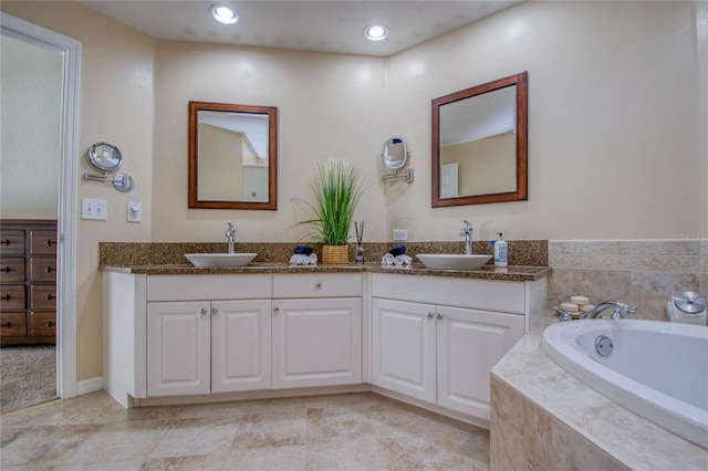 bathroom with a relaxing tiled tub, tile patterned floors, and vanity