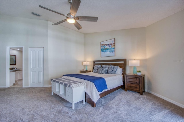 bedroom with connected bathroom, light carpet, a textured ceiling, and ceiling fan