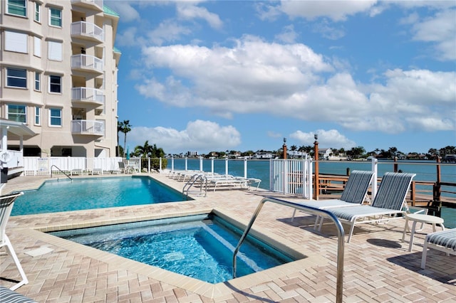 view of pool featuring a patio, a water view, and a community hot tub