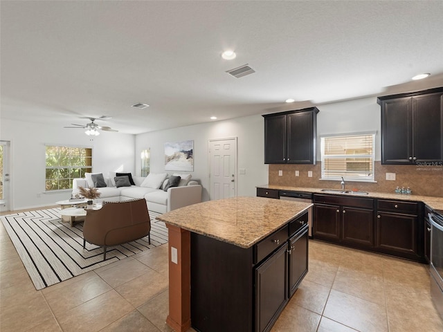 kitchen with sink, decorative backsplash, light tile patterned flooring, and a kitchen island