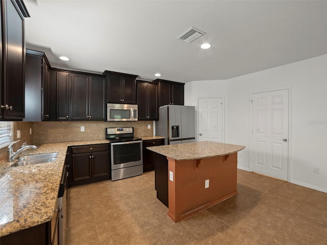 4734 Chatterton Way, Riverview, FL 33578 - kitchen with stainless steel appliances, a sink, tasteful backsplash, a center island, and light stone countertops