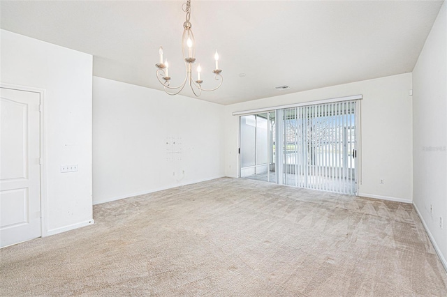 carpeted spare room featuring an inviting chandelier