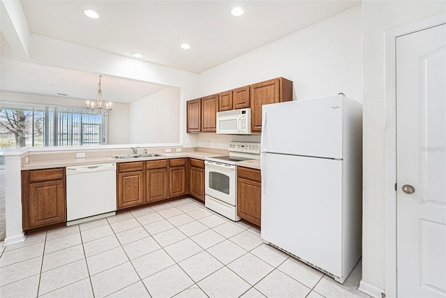 kitchen featuring sink, hanging light fixtures, kitchen peninsula, a notable chandelier, and white appliances