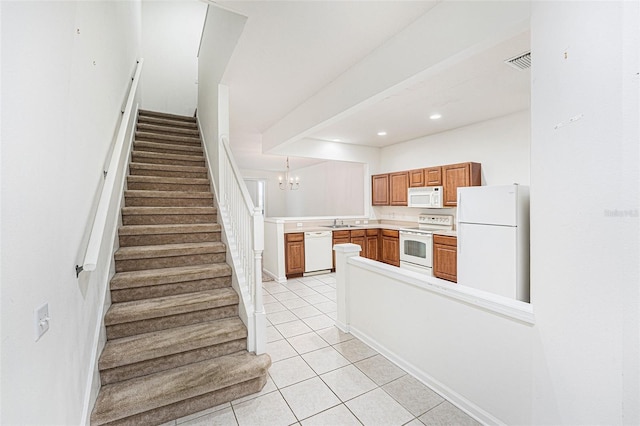 kitchen with sink, hanging light fixtures, light tile patterned floors, kitchen peninsula, and white appliances