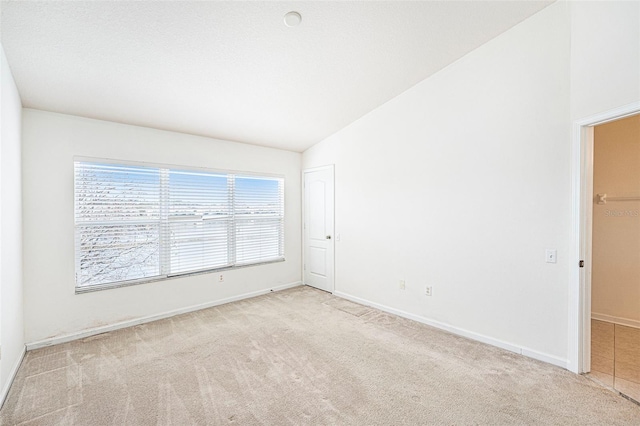 carpeted spare room featuring vaulted ceiling