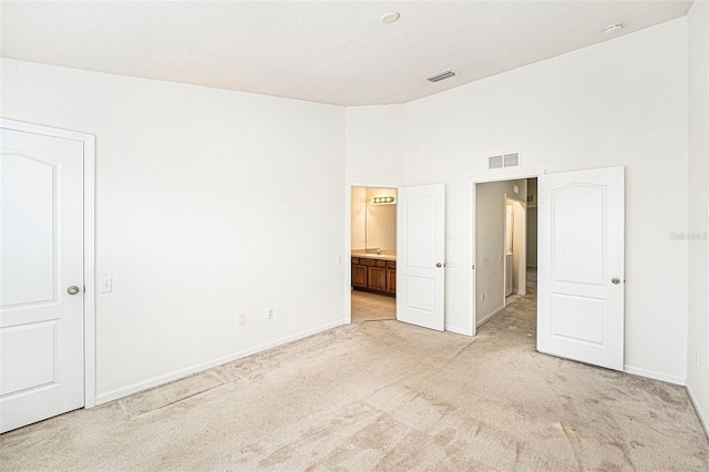 unfurnished bedroom with connected bathroom and light colored carpet