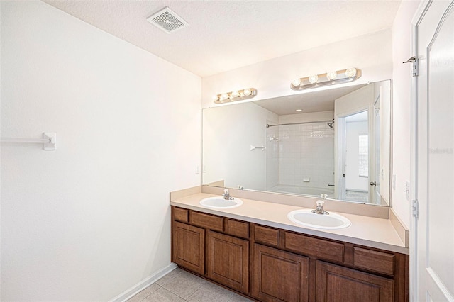 bathroom with tiled shower / bath, tile patterned floors, vanity, and a textured ceiling