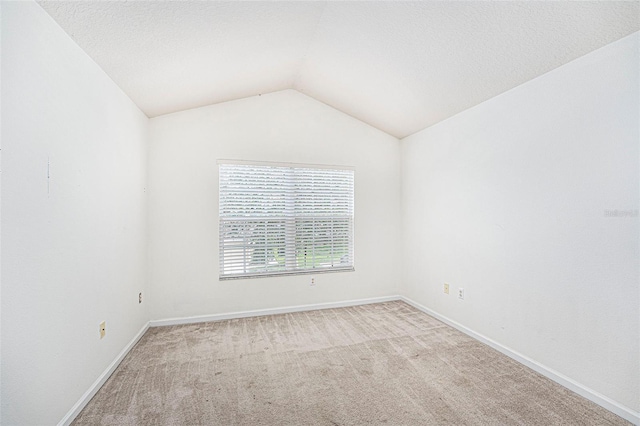 carpeted spare room featuring lofted ceiling and a textured ceiling