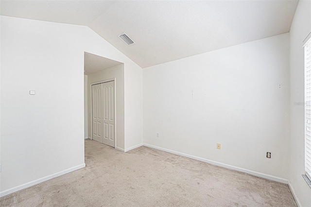 carpeted empty room with lofted ceiling