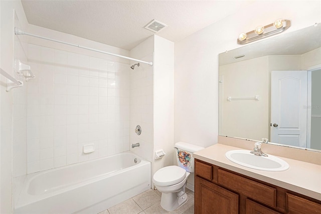 full bathroom featuring tile patterned flooring, tiled shower / bath combo, vanity, a textured ceiling, and toilet