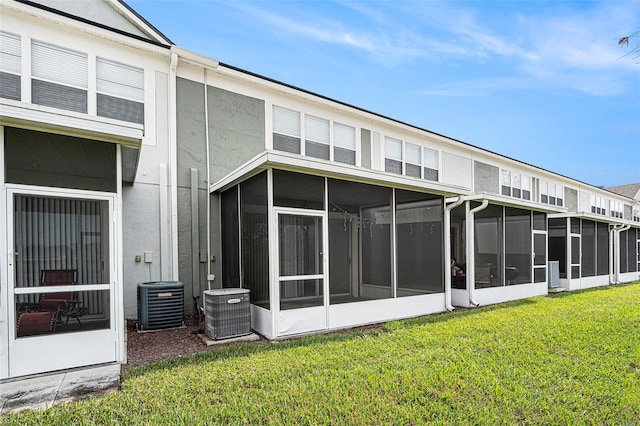 back of house with a lawn, a sunroom, and central air condition unit