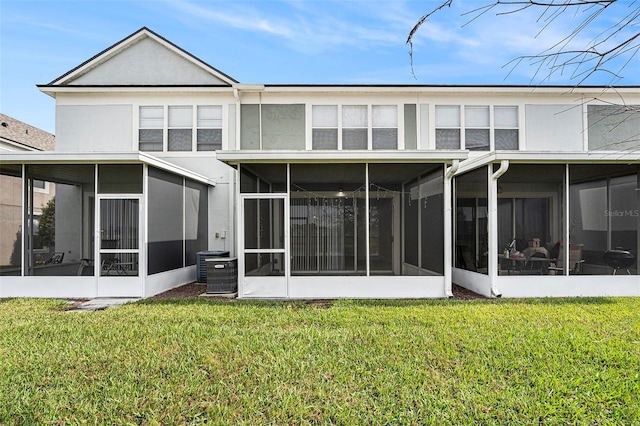 back of property with a sunroom, a yard, and central AC