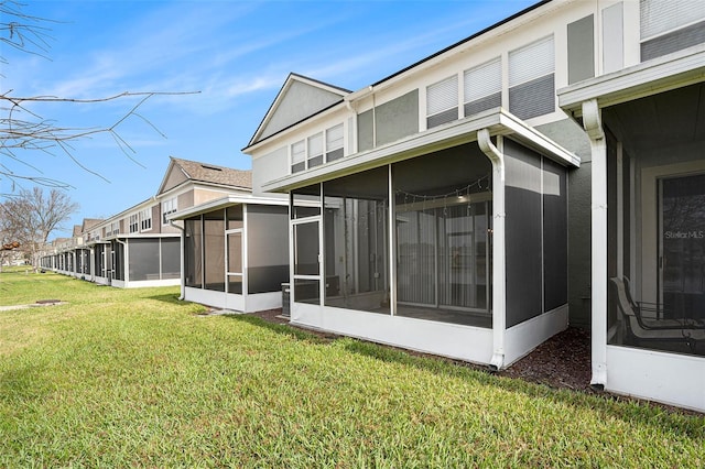 back of property with a lawn and a sunroom