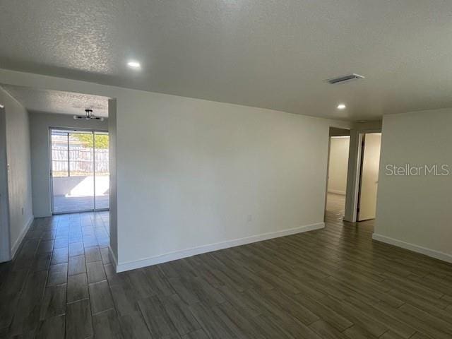 unfurnished room featuring dark hardwood / wood-style flooring and a textured ceiling