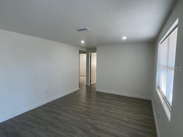 unfurnished room with dark wood-type flooring and a textured ceiling