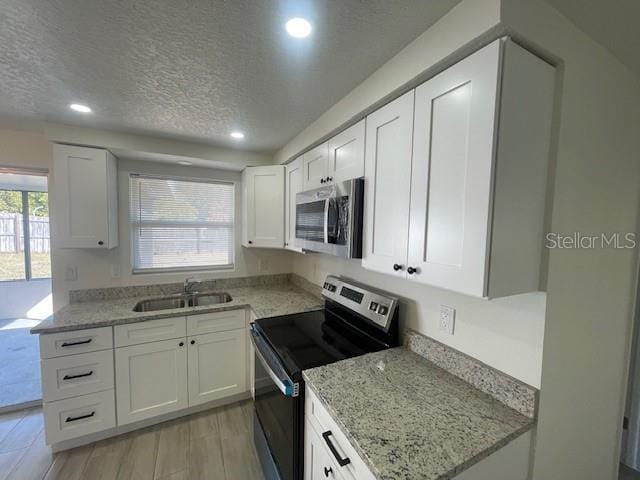 kitchen with stainless steel appliances, plenty of natural light, sink, and white cabinets