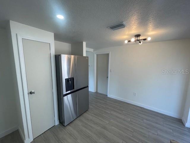 kitchen featuring wood-type flooring, stainless steel fridge with ice dispenser, and a textured ceiling