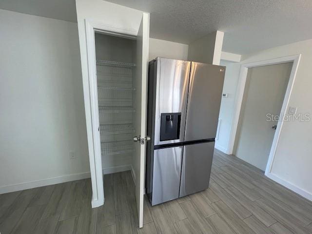 kitchen with a textured ceiling and stainless steel refrigerator with ice dispenser