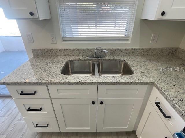 kitchen featuring white cabinetry, sink, and light stone counters