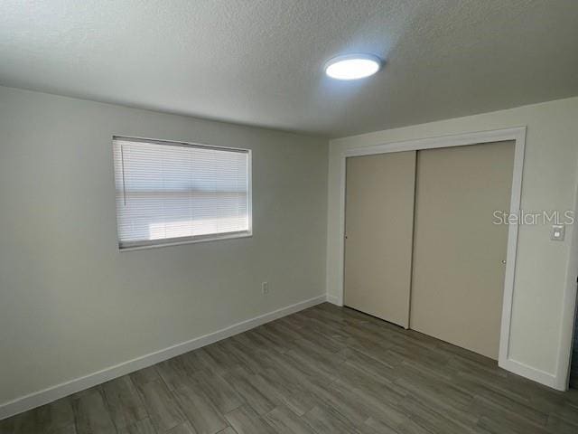 unfurnished bedroom with a closet, wood-type flooring, and a textured ceiling