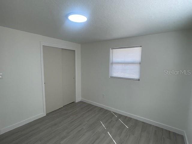 unfurnished bedroom with hardwood / wood-style flooring, a textured ceiling, and a closet