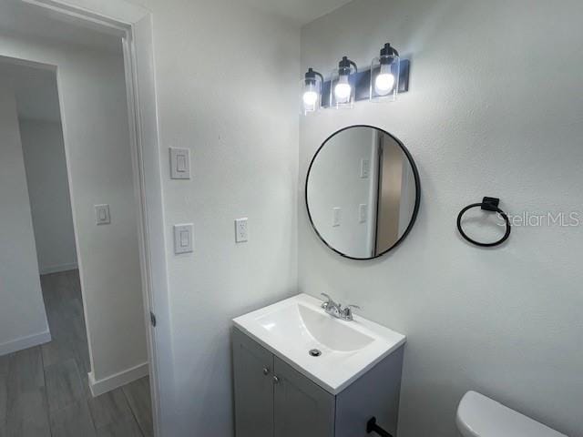 bathroom with vanity, wood-type flooring, and toilet