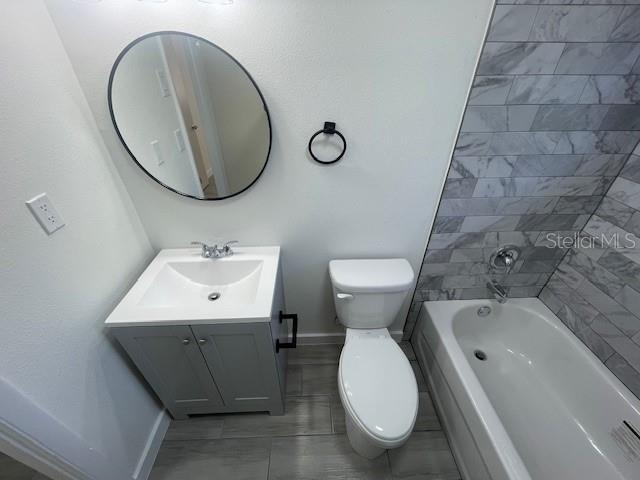 full bathroom with vanity, tiled shower / bath combo, and toilet