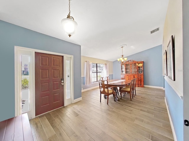 dining room featuring an inviting chandelier, vaulted ceiling, and light hardwood / wood-style floors