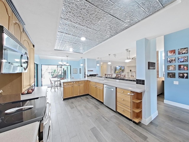 kitchen featuring decorative light fixtures, light wood-type flooring, light brown cabinets, appliances with stainless steel finishes, and kitchen peninsula