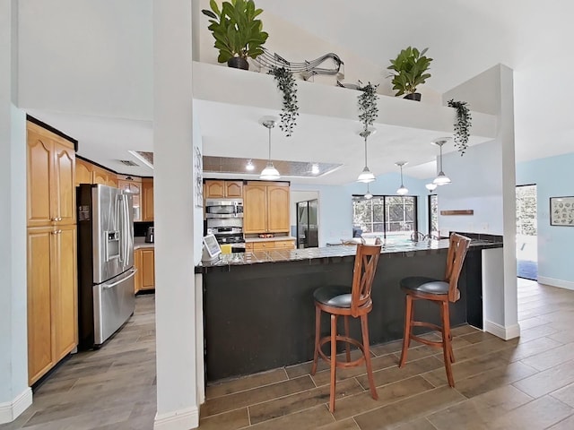 kitchen featuring high vaulted ceiling, stainless steel appliances, a kitchen bar, decorative light fixtures, and kitchen peninsula