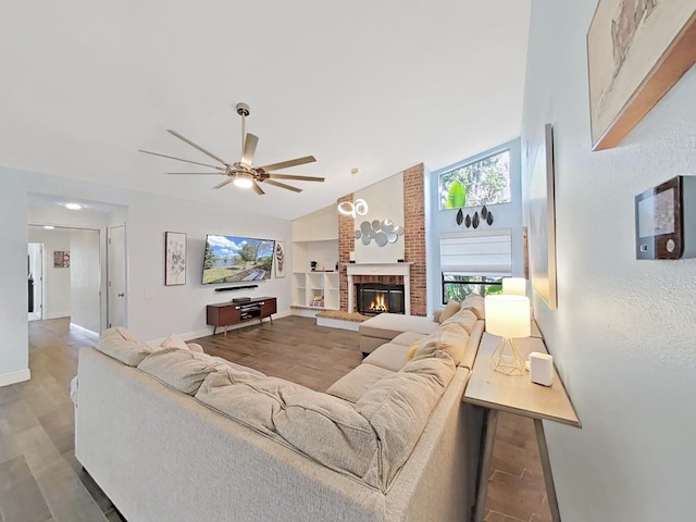 living room with vaulted ceiling, wood-type flooring, a brick fireplace, and ceiling fan