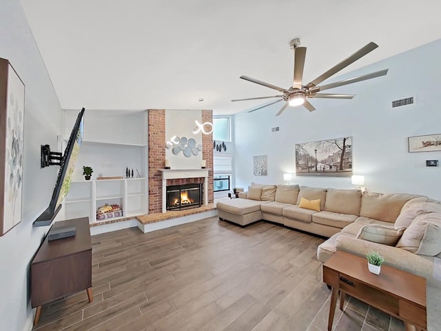 living room with a brick fireplace, hardwood / wood-style floors, lofted ceiling, and ceiling fan