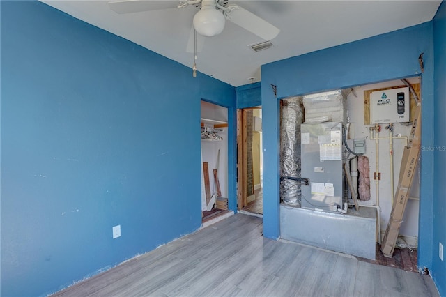 unfurnished bedroom featuring ceiling fan, wood-type flooring, and water heater