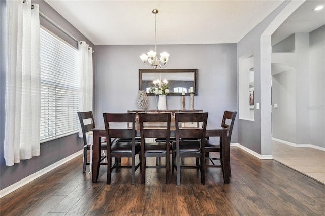 dining space with dark wood-type flooring and a notable chandelier