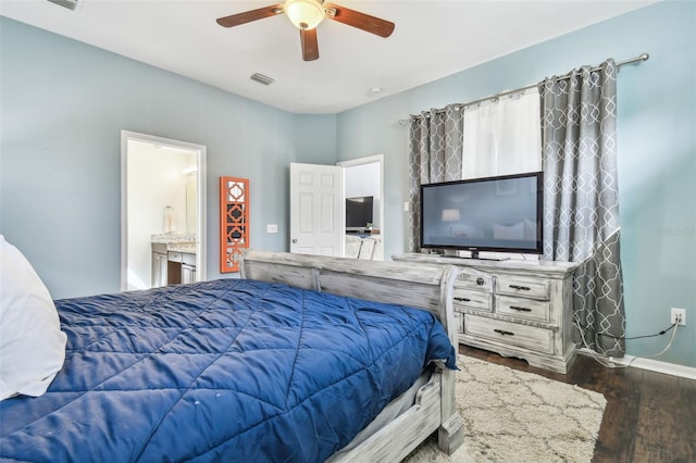 bedroom with dark wood-type flooring, ceiling fan, and ensuite bath