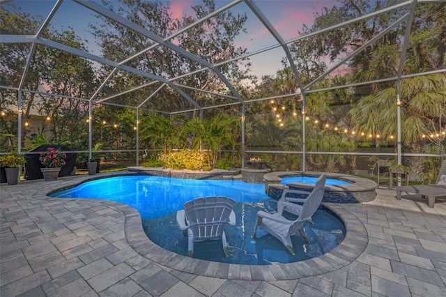 pool at dusk with an in ground hot tub, a patio area, and glass enclosure