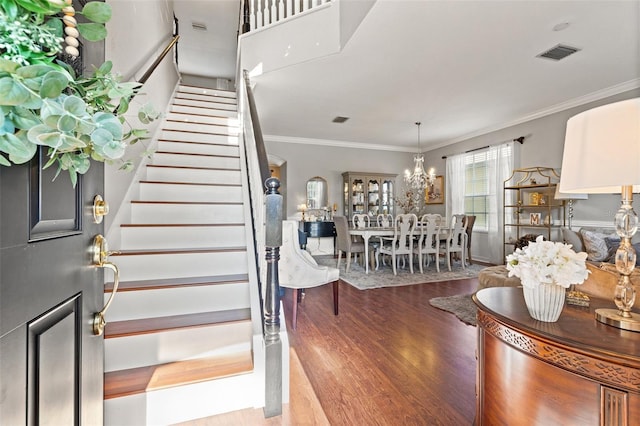 entryway featuring an inviting chandelier, crown molding, and light wood-type flooring