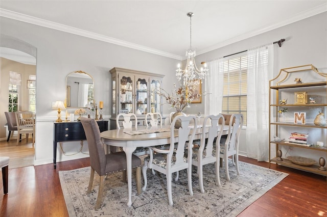 dining room featuring dark wood-type flooring, crown molding, and a notable chandelier