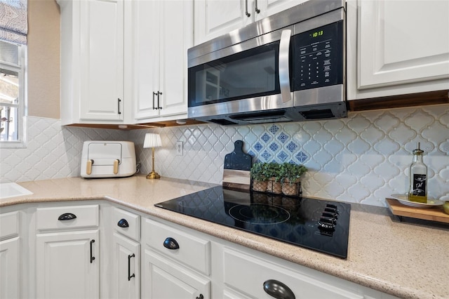 kitchen featuring black electric cooktop, tasteful backsplash, and white cabinets