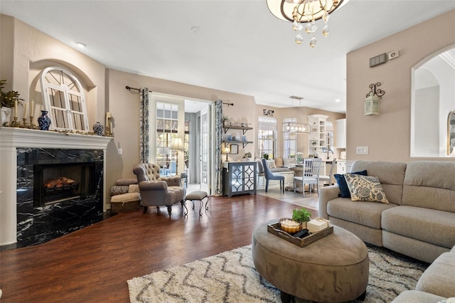 living room featuring a premium fireplace, dark hardwood / wood-style flooring, and a notable chandelier