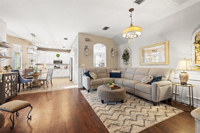 living room featuring vaulted ceiling, dark wood-type flooring, and a notable chandelier